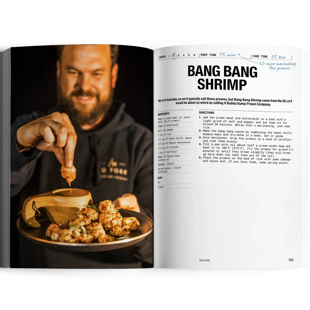 Open cookbook showing a recipe for 'Bang Bang Shrimp' with a person adding sauce to food.